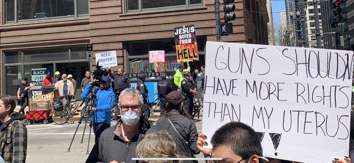 As the crowd defending abortion access grows outside the Dirksen federal courthouse, another, smaller group across the street hoists signs about prayer and Jesus.   Be a man and stand up for the rights of the unborn a man says into a microphone