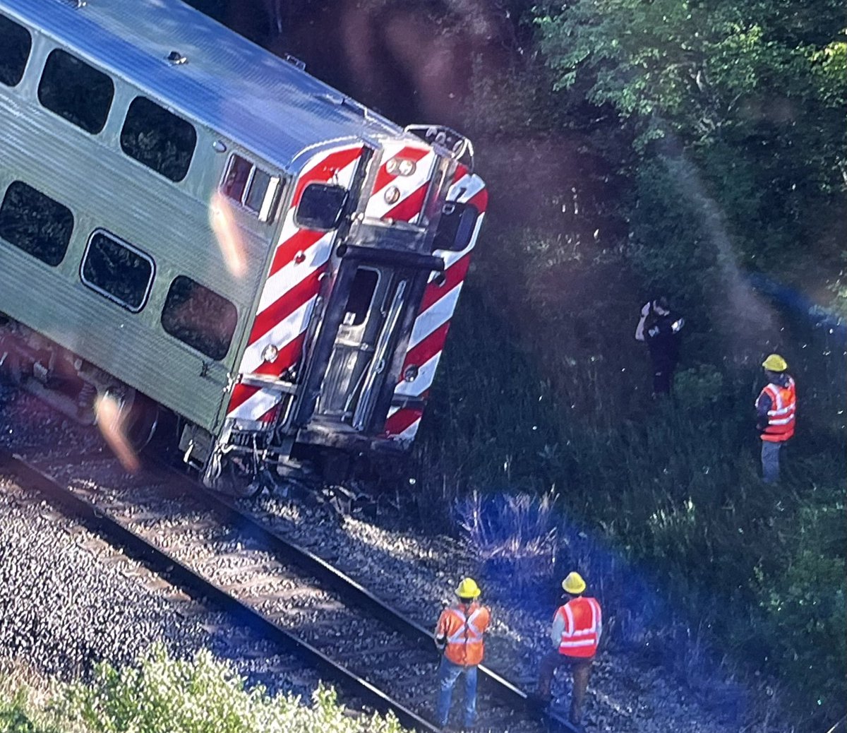 METRA engineering personnel examine the derailed end of the cab car on MD-N train 2116 after it hit a truck on the rural Hainesville Road crossing south of Route 120. One passenger was hurt & the truck driver died at the scene. 